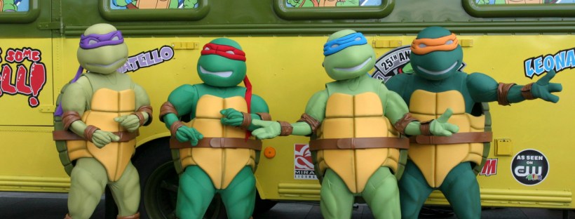 Ninja Turtles standing in front of a bus.