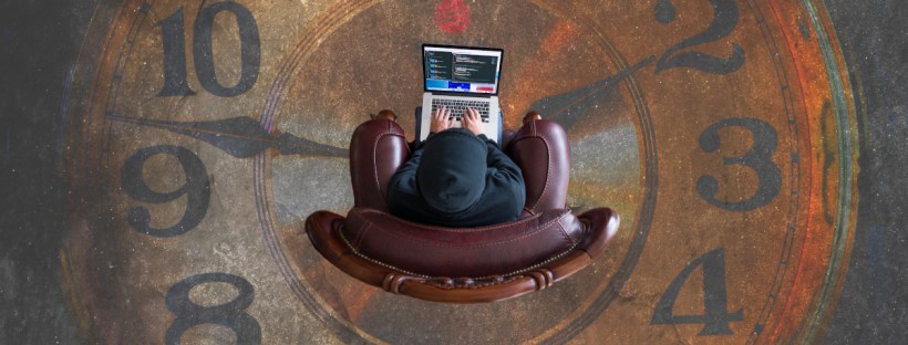 You're looking down on a person sitting on the floor holding a laptop. The floor tiles are designed like a clock. The person is placed at its centre.