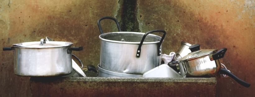 This is a painting of dirty dishes stacked in a large sink. It's mainly pots and pans.