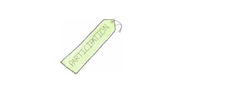 This is a light green-coloured ribbon. It’s sitting flat on a 30° angle, pointing to the right. The top of the ribbon is shaped like an arrow head. There’s a hole near the top, with a piece of black string looped through it and knotted at the end. This allows the ribbon to be hung. The bottom of the ribbon is jagged, like it was torn from a piece of perforated cloth. The word “participation” is stitched in black in the ribbon’s centre. The word is written in capital letters.